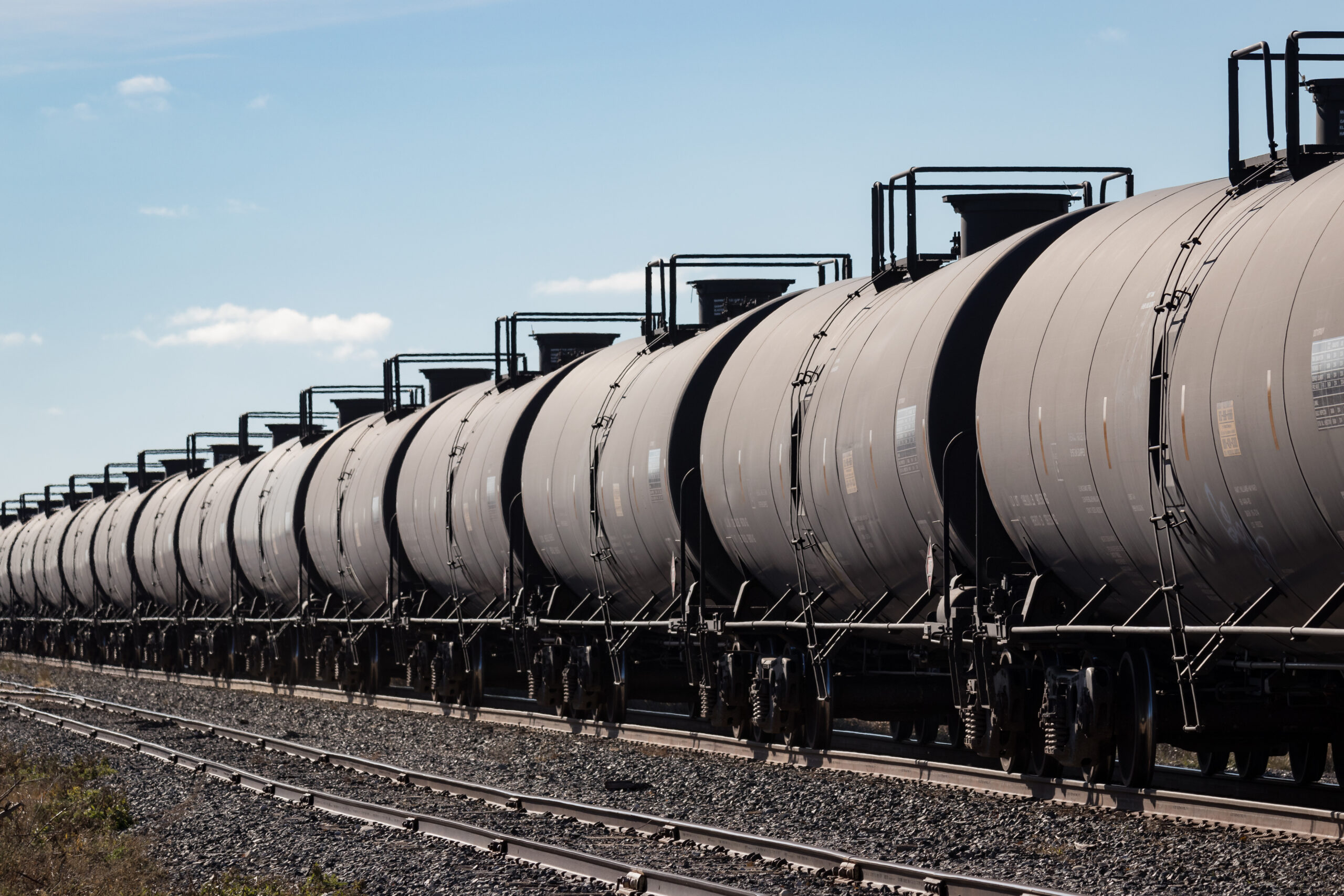 Line of Black Tank Cars Under A Blue Sky